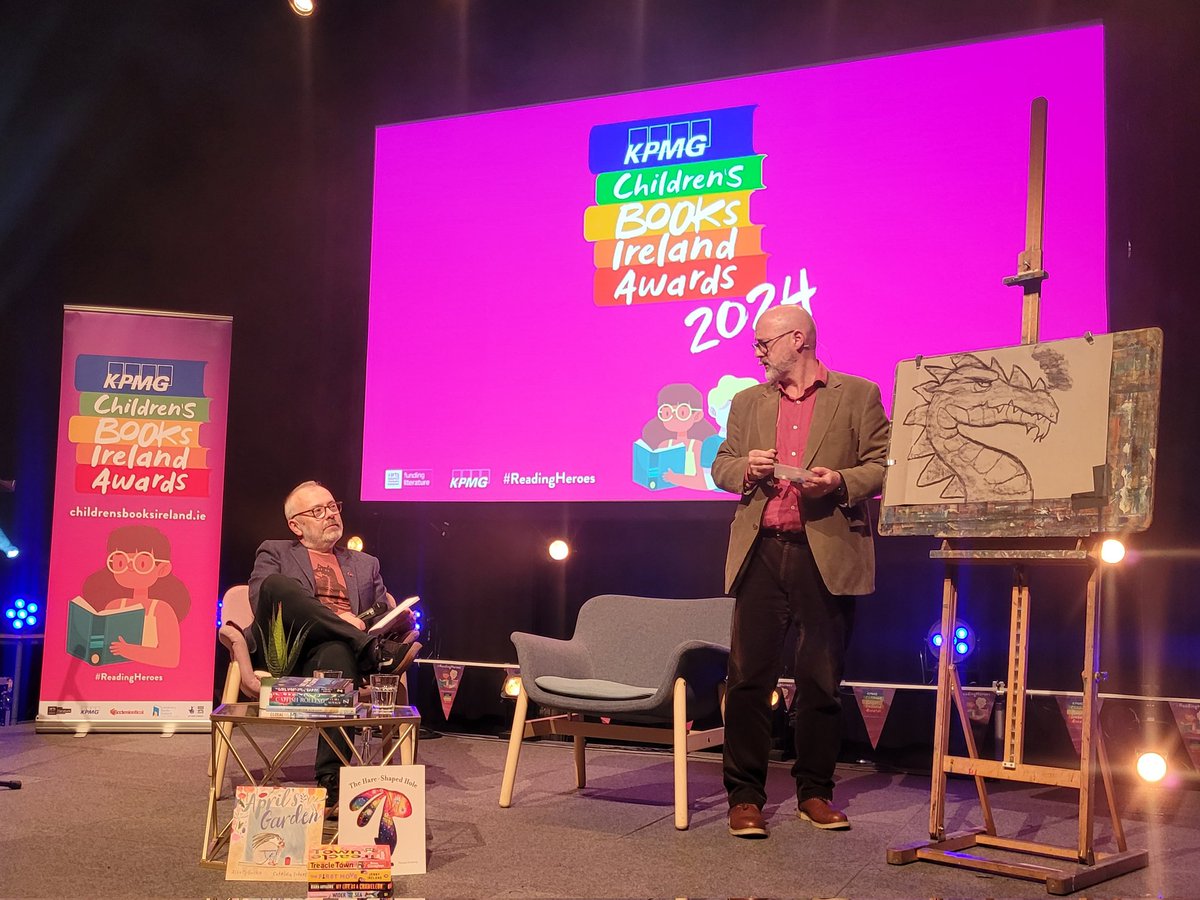 Now, we're being treated to a very unique interview format, as Rick picks shortlistee @PJLynchArt's brain while he sketches out this magnificent dragon for our audience 🐉 #ReadingHeroes
