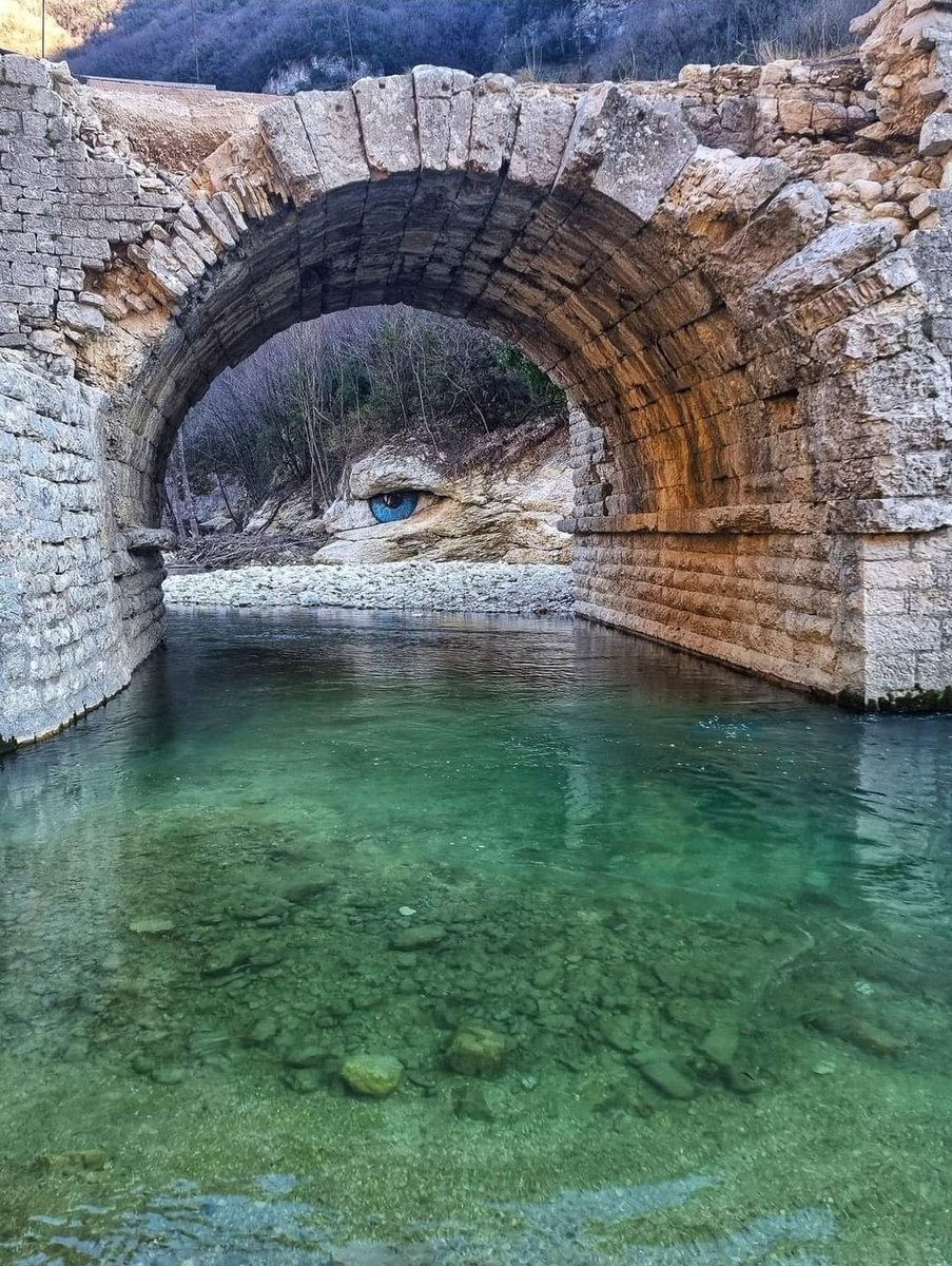 E' apparso sulle pietre del fiume Burano nelle #Marche, un occhio che fissa il ponte romano. Un simbolo per attirare l'attenzione sul bene storico lasciato all'abbandono dopo l'alluvione del 2022. Dall'iride azzurra, la pupilla scura e la roccia superiore come sopracciglia.