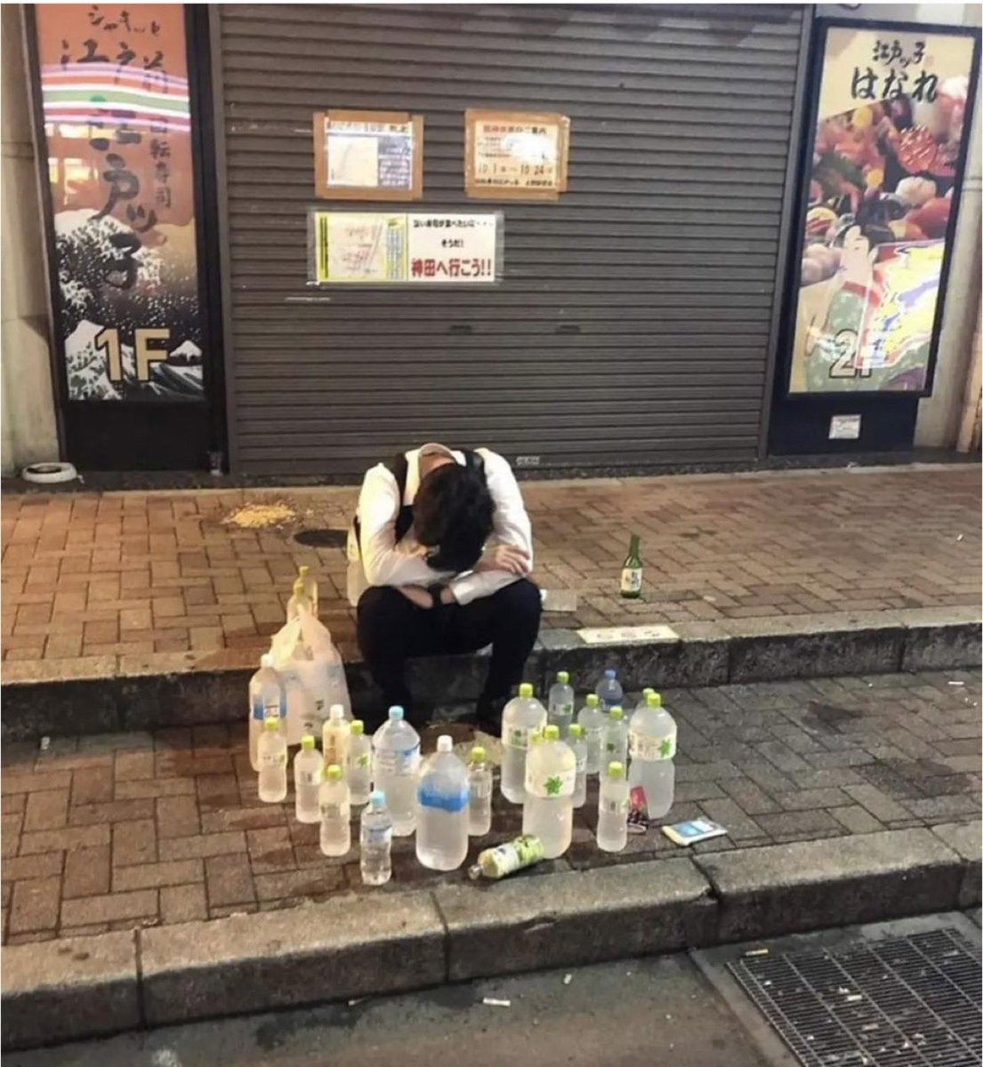 🇯🇵This is Japan. This man got drunk and fell asleep on the street. Then a kind person placed a bottle of water in front of him and walked away. Other people did the same, so he was surrounded by water.🤣🤣🤣