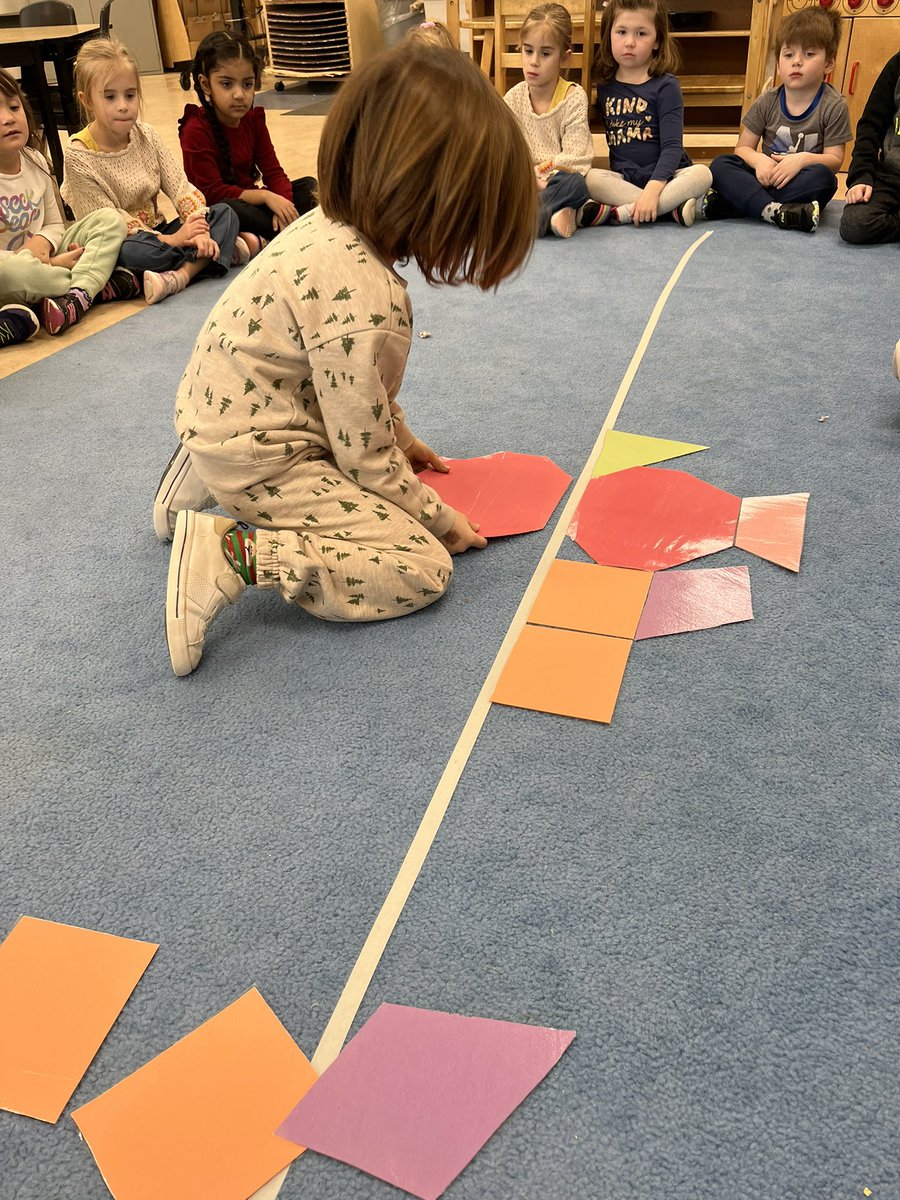 Learning about symmetry using giant shapes and a line of symmetry on our carpet. Can you finish the symmetrical picture? @APSMustangs #EarlyYears #Math