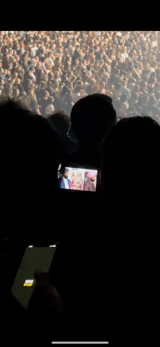 At <a href="/the1975/">The 1975</a> gig, -one person is watching a Bollywood film and another guy is checking the football scores