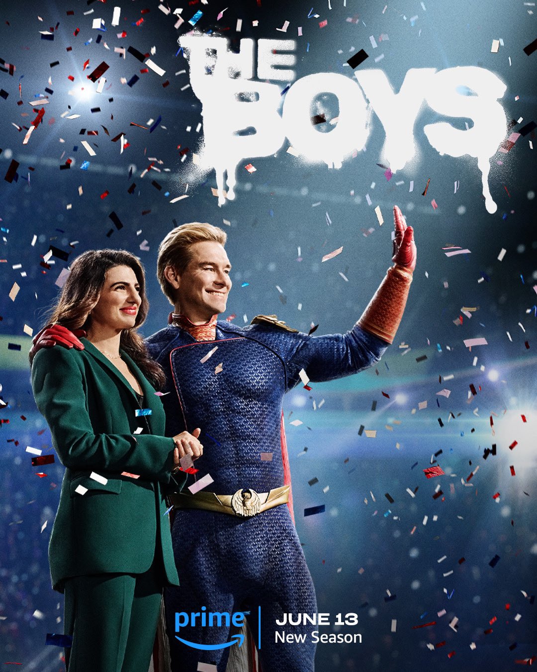 Homelander and Victoria Neuman from The Boys. He stands with one arm around her and one arm waving. She’s in a green pantsuit, classic Victoria. Confetti comes down all around them. Text at the bottom reads Prime, June 13, New Season.