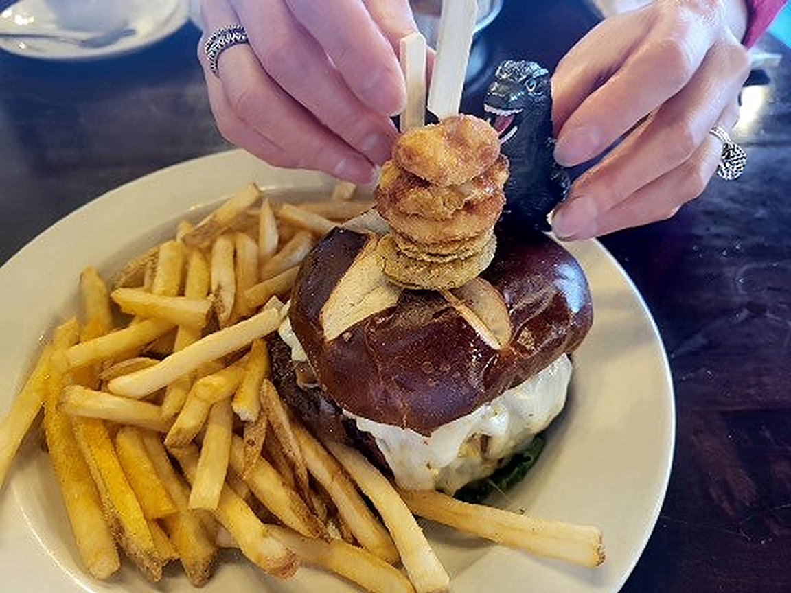 Behind the scenes with social media influencer and icon #Meatzilla as he is strategically posed with another scrumptious meal.  #burger #beef #friedpickles #cheesecurds #cheese #egg #pretzelbun #fries #lunch #carnivore #foodie #delicious  🐮🧀🧅🥒🥚