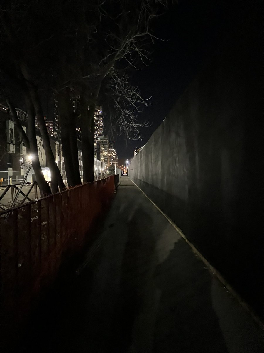 FOMossPark's tweet photo. @Metrolinx’ black hoarding on the west side of the park along the path running north/south beside the Moss Park Armoury leaves the pathway in darkness.   If you look closely you will see a figure lurking in the shadows. It is a long stretch to run back to safety if needed. https://t.co/BMIcOz57Yk
