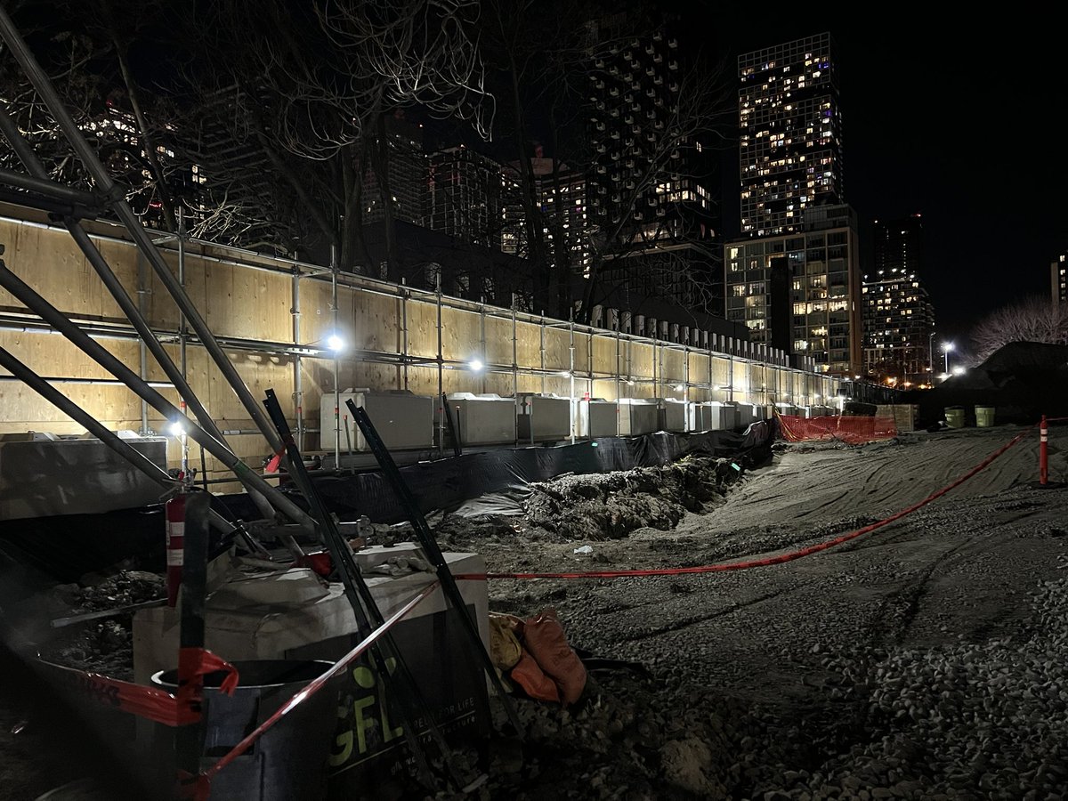 FOMossPark's tweet photo. @Metrolinx’ black hoarding on the west side of the park along the path running north/south beside the Moss Park Armoury leaves the pathway in darkness.   If you look closely you will see a figure lurking in the shadows. It is a long stretch to run back to safety if needed. https://t.co/BMIcOz57Yk