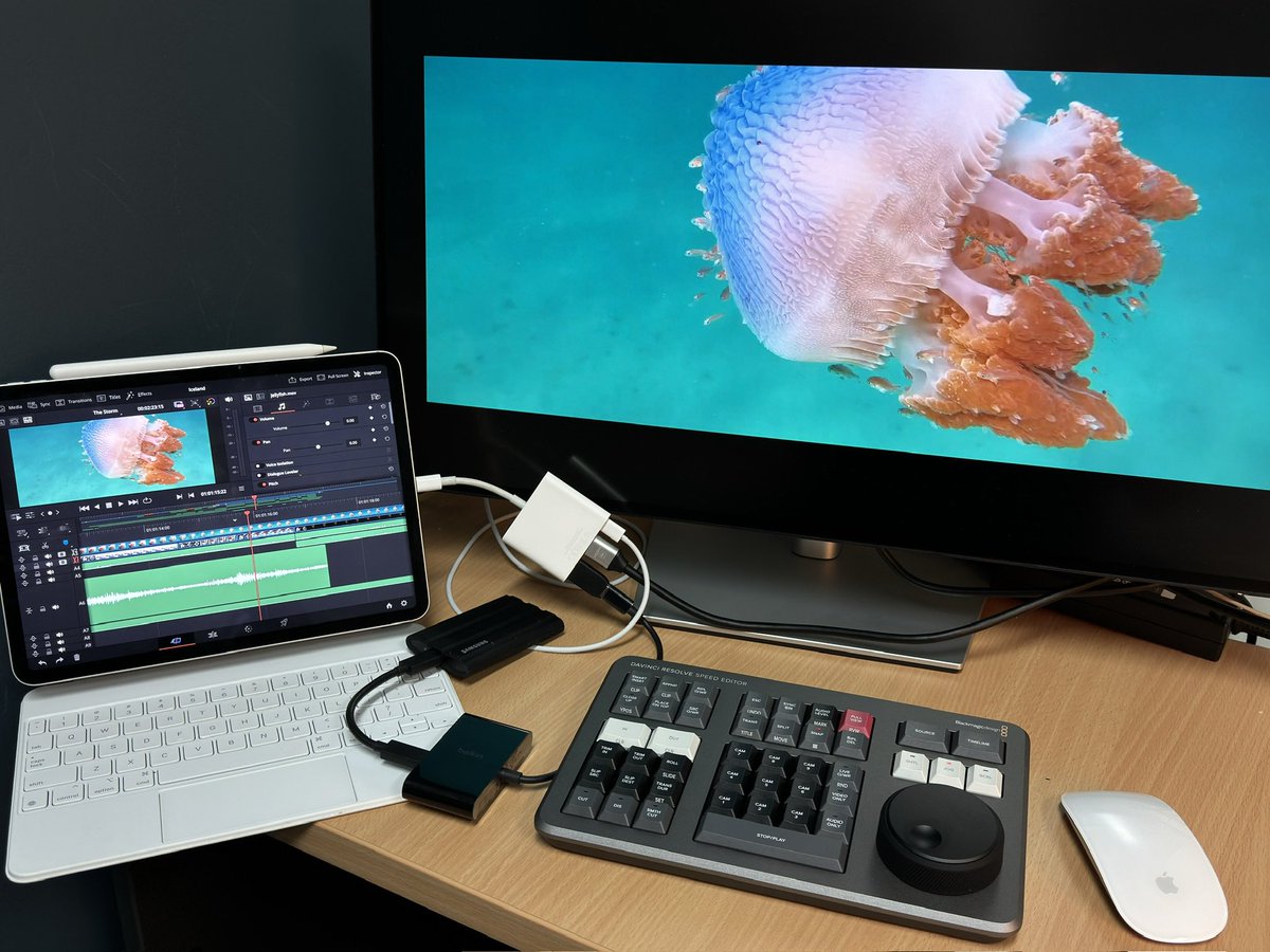 Mobile-based edit suite: iPad running DaVinci Resolve connected to a speed editor, external monitor, external drive, power, and a Magic Mouse. The speed editor has roughly the same footprint as this 11” iPad so they both pack neatly into my mobile journalism back pack.