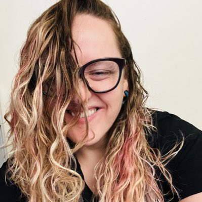 danigraybill's tweet photo. #NewProfilePic image description:  A close-up portrait of a woman with long curly hair that covers half of her face. She is looking at the camera, smiling. She is wearing large-framed glasses, a black shirt, and a scarf. The background is a plain white wall. https://t.co/53HqNlNKup