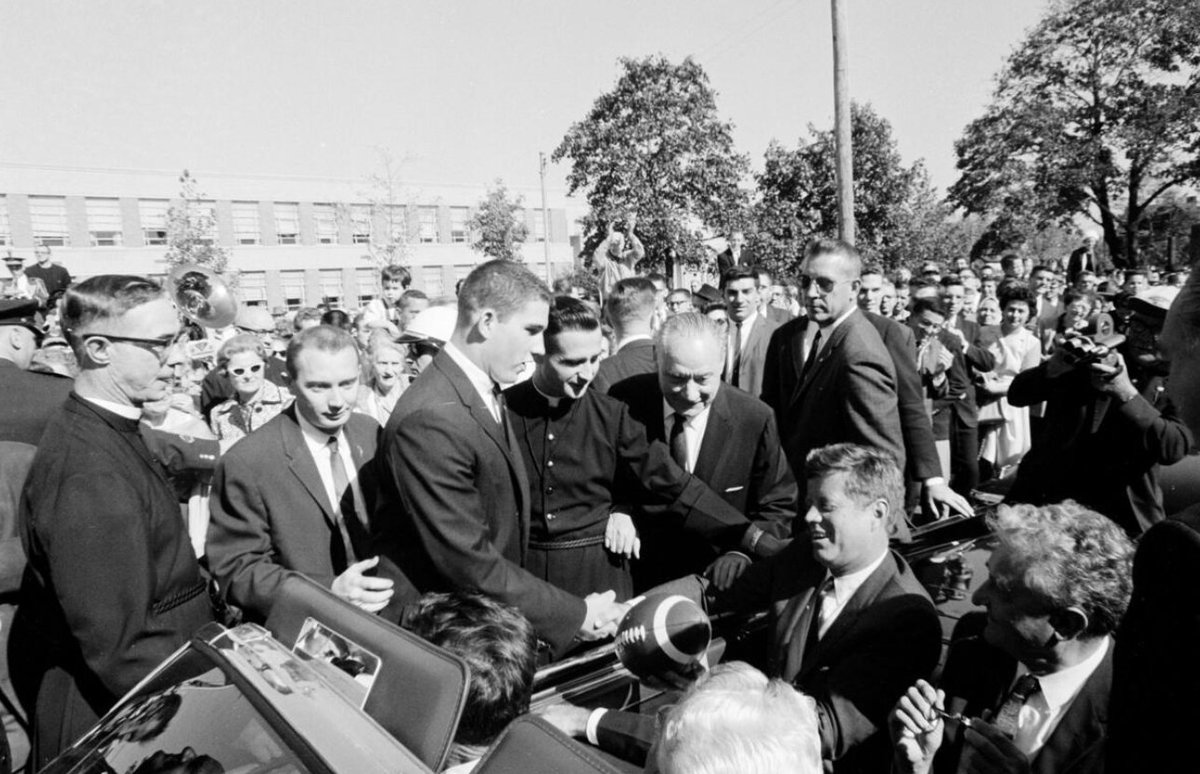 🇺🇸 To commemorate Presidents' Day, we're excited to share this incredible throwback! In 1962, the legendary President John F. Kennedy visited our campus. As the motorcade approached, the Marching Eagles played and Bob Cutter '63 proudly presented a football from the student body.