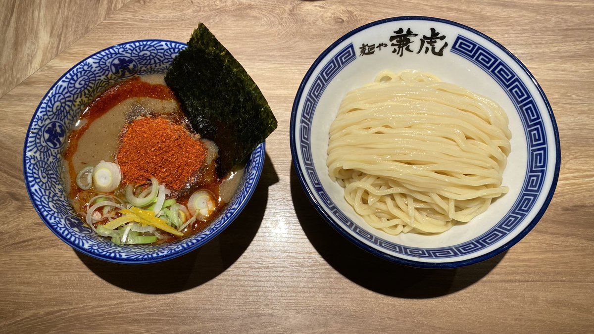 ogopoco26's tweet photo. JR博多駅構内・めん街道「麺や 兼虎」
辛辛つけ麺1200円麺300g辛さ基本 

「辛い豚骨魚介つけ麺」の両横綱「兼虎」と「魚雷」が福岡場所でがっぷり四つに組み合う！

先日の「魚雷 天神店」の記憶がまだあるうちに「兼虎」も食べてみようかな？

と博多駅に来てみると、いろいろ変わっていた

________________________

変化①製麺所

まず目についた変化は三河屋製麺の段ボール箱、ラベルには「生中華麺」とあり。創業の地で営業していた頃は三河屋製麺だったので、製麺所が変わったというか戻ったというべきか

変化②メニュー名

去年7月にメニューが「極濃つけ麺」「極辛つけ麺」に変わったはずが、いまは元に戻っている

変化③あつもり

あつもり可能になっている！いつから？
________________________

甲子園風に言うと7ヶ月ぶり6回目の訪問になるけど、つけ汁を飲むたびに思う。
粘度はかなり高いけどさほど重たさはないこの感じ、ベジポタ風だよなぁ、と。

そしてポイントは粉末。魚粉、唐辛子の粉が混ざっての甘辛さ！

もしできるなら、粉末別皿でこのつけ汁を楽しんでみたい。

麺は以前とは風味がかなり異なっていて、艶やかガッチリで美味くなった！

総じて、やっぱり間口が広いつけ麺だ。

かたや、東京の名店「井の庄」出身の血筋の良いつけ麺
かたや、その東京に憧れてのし上がってきたつけ麺

同ジャンルでも全く異なるつけ麺、福岡場所の今後が楽しみだ