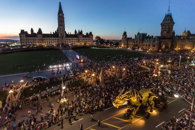 Vue aérienne de la Colline du Parlement et du dragon doré du spectacle de La Machine déambulant le long de la rue Wellington lors des célébrations du 150e anniversaire du Canada.