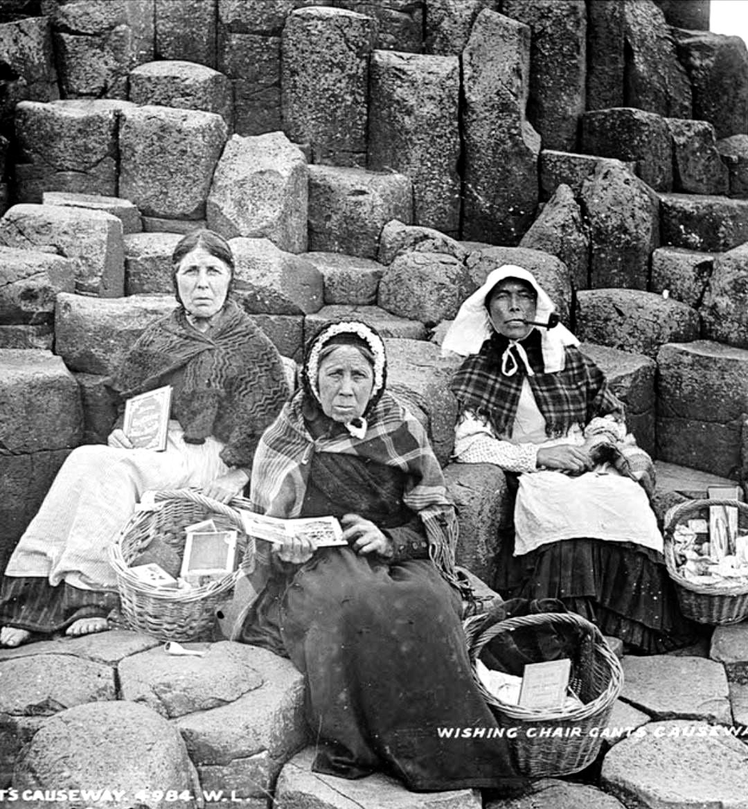 Three Irish women sitting on the Giant’s Causeway in County Antrim, selling souvenirs to tourists in 1900. Giant’s Causeway is an area of about 40,000 interlocking basalt columns, the result of an ancient volcanic fissure eruption.