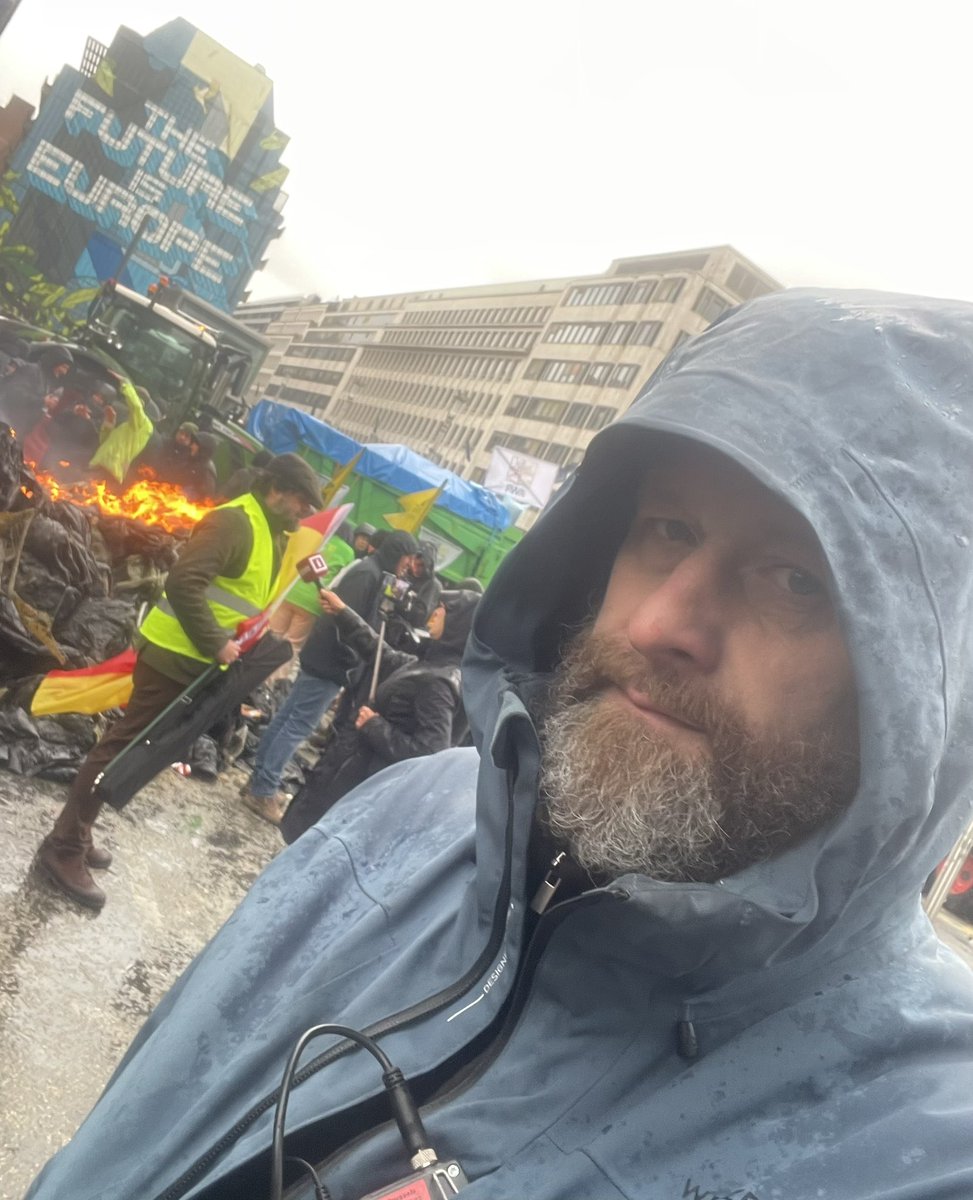 TiloGummel's tweet photo. Unkempt man standing in the rain wondering why farmers protests always lead to burning tires. 
Where is the #Sustainability in that? 

#Brussels #protest https://t.co/bPsD7dODOp