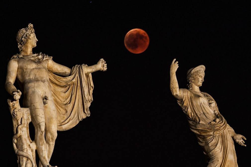The blood moon is framed by the statues of Hera and Apollo in Athens