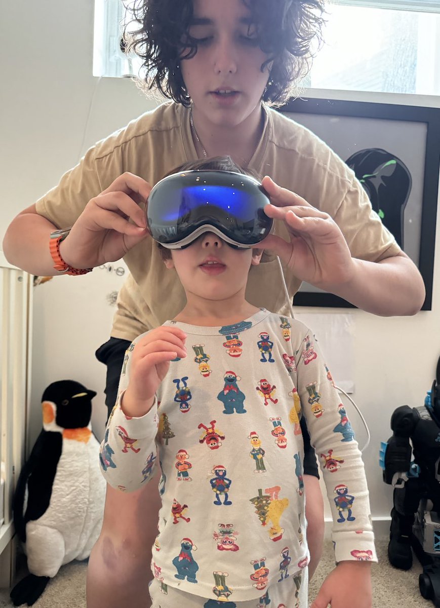 wjj_'s tweet photo. Screen Mirroring : makes the AVP better than Beer Goggles

As an AppleChild growing up with their tech in the early 80s, I’ve had the pleasure of experiencing all their juicy products from the seeds up.

Few favorites (pre phone) were the IIci, the first flat panel studio Display and of course the ultimate app : MacPlaymate, the finest Black and White low pixel experience in the compuworld. Then the phone and now The Apple VisionPro.

You’ve already read about the epic fanciness of the AVP. The tech, the power, the build and of course the price. Apple has been notorious with this playbook since the original Mac, and if you’re like me and have given many jet skis and college tuition in the Apple enclosed secret garden, you’ll find your VisonPro yet another Mac ID controlled device in your Apple Garage.

I found the device to operate exactly like the iOS you’re familiar with the last 200+ versions. Message and Safari and FaceTime and Music and Spotlight and Control Panel are all bolstered with a Double M2 processor with a micro-quintillion eye-tracking display. And yes, it will still lock you out for 30 seconds after your first failed passcode attempts… but this time in 8K!

But there is one more thing the VisionPro executes brilliantly. Perhaps worth every penny of the $4500 aging hardware price. Perhaps the first true VR headset that destroys the cool tech geek who never shares the device and just describes it as “Holy Fuck” and “Whoa, you gotta see this” while everyone else is bored and sitting in bowls of pudding.

Yes my friends, this feature that you know so well from your fancy phones is the one and only Screen Mirroring. You’ve used it countless times when showing off your videos or streaming illegal content to your living room screens. That picture in picture icon which pairs so well with AirPlay and Apple TV now is the gateway to the party of 2030.

When you see a headseter pulling imaginary strings and touching fake butterflies you can now feel what they’re feeling : see what they’re controlling : and still go grab a drink while they're locked in the control helmet driving the party. 

We all know from the early prototype Apple gear, from brick screens to iphones to, the Vision Pro IS its first version, and as time drains on, so will the size of this thing.

I asked my brainiac nieces and nephews when this will turn into a Black Mirror contact lens? 2032 is the going prediction… perhaps I can enjoy that experience in the AVP Old Folks home…