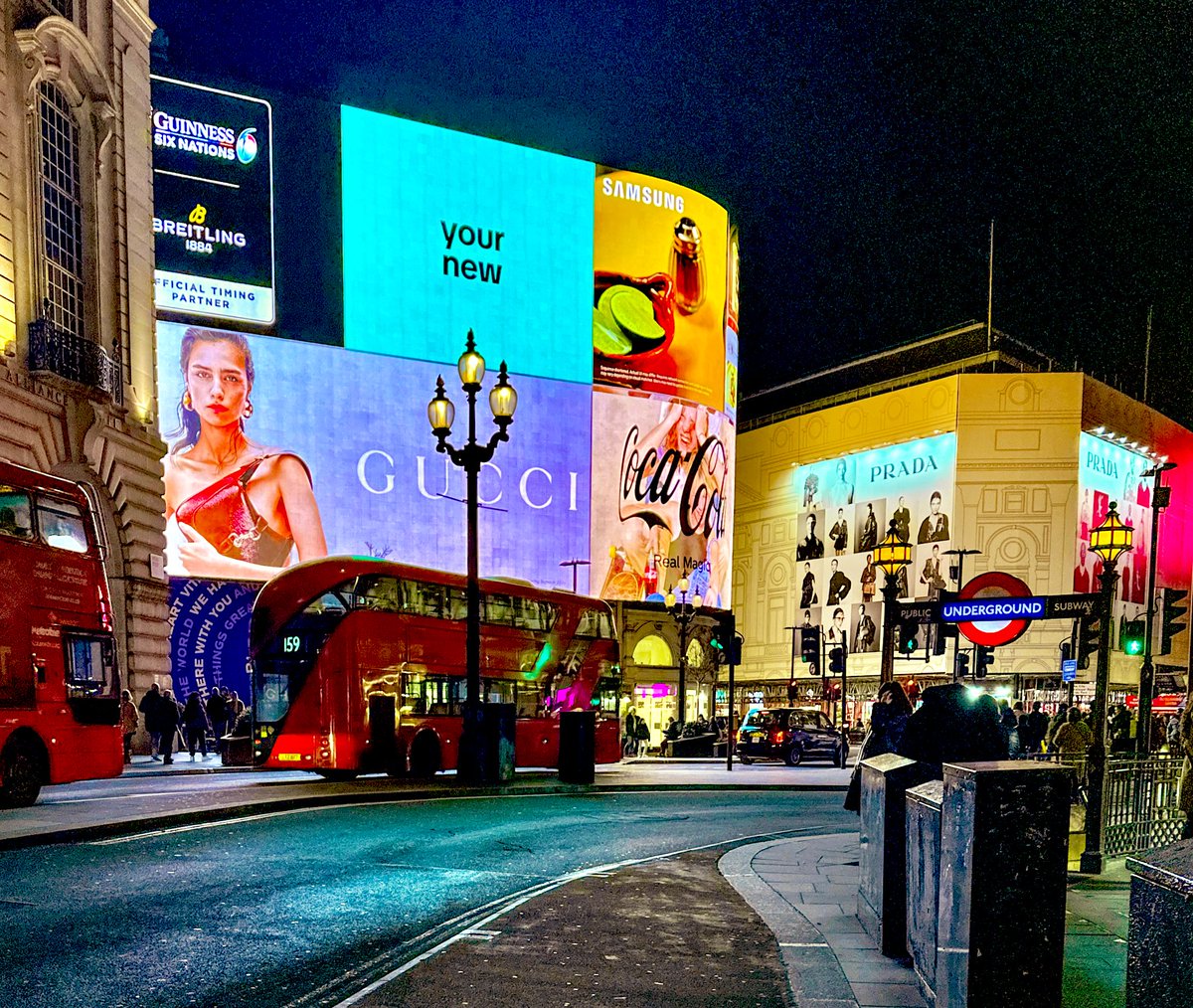MrTimDunn's tweet photo. Piccadilly Circus at night: 1960s vs 2024.
Elmar Ludwig (of John Hinde Studio) shows a London long gone, but my snap of the scene shows surprising similarities. Sure,  buses have ballooned & decarbonised, street furniture shifted and ads are digital. But. The buses are still “Routemasters”, the lamps are still similar shapes, the curb is still there and the ads… well. Coca-Cola still blinks, Guinness is still sponsoring something, and the Guinness Clock, well - it’s not quite a clock; but TikTok’s there instead. BP isn’t in this party (ULEZ, prob keeps it out) and maybe there’s less need for airlines now - Samsung means cheap international communication, I guess. Through it all, the Underground roundel still shines. (Prints of E Ludwig’s photos are available from @TPGallery https://t.co/5WEKLVOF5U)