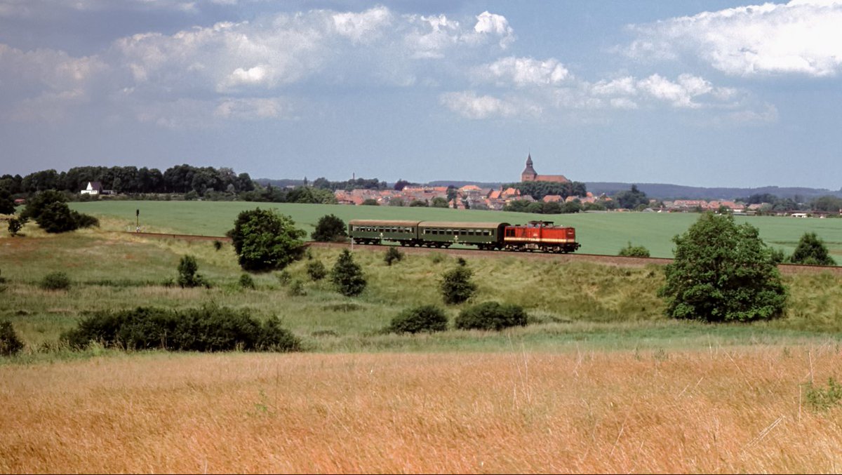08.06.1992
Was ein Bild, Idylle auf Feld und Dorf.

Eine 202er wieselt bei Sternberg mit ihrem P7619 durch die Lande. Die Strecke zwischen Wismar und Karow als klassische Nebenbahn.