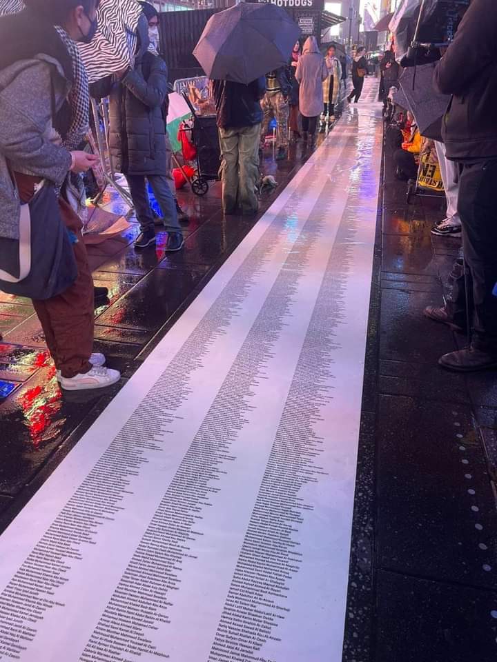 OnlinePalEng's tweet photo. Protestors display the names of Palestinians killed by the Israeli occupation in Gaza during a vigil in Times Square, NYC. https://t.co/031TZpTplC