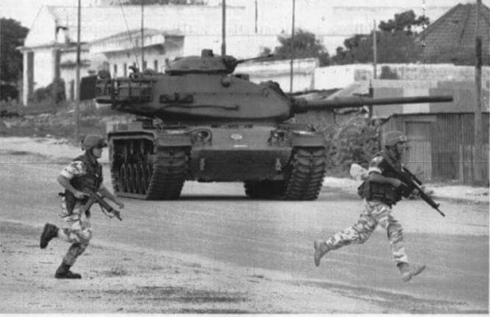 Italian soldiers run past a M60A1 during the Battle at Checkpoint Pasta in Somalia (2th July, 1993)