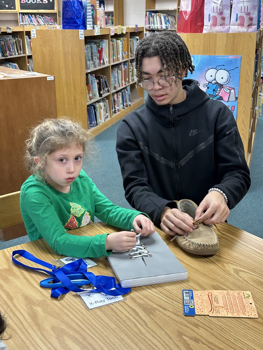 Young tiger Ella, working on tying shoes at one of the VETTS Clinic stations at Wilcox Elementary!

The station helps young tigers learn how to tie shoe laces or advance their techniques.

Great job being Tiger Strong Ella!

#TCSDProud #TigerStrong 
@TwinsburgSupt