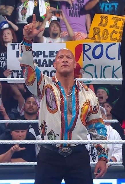 ChandranTheMan's tweet photo. The Rock does the "L" again and Paul Heyman notices it this time.  I'm loving all these little details in the story. https://t.co/ErWcnUbTch
