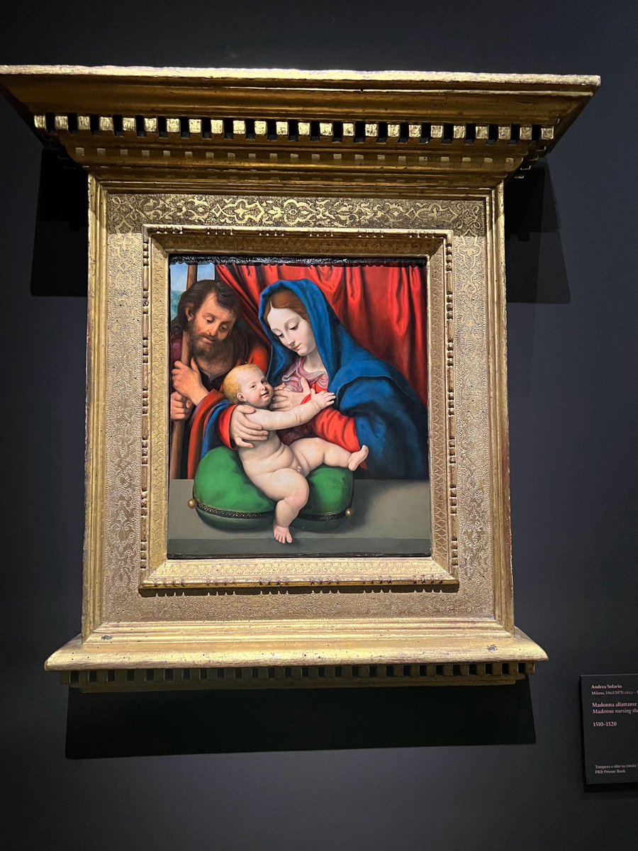 Oltre al lirismo e al virtuosismo pittorico di Andrea Salario, c’è una delicatezza fragrante, umanissima, nel sapere che anche la madre del dio incarnato, avvolta del blu dei cieli, ha bisogno di un cuscino per allattare. E il suo bambino sorride (rarità) anche al pittore.