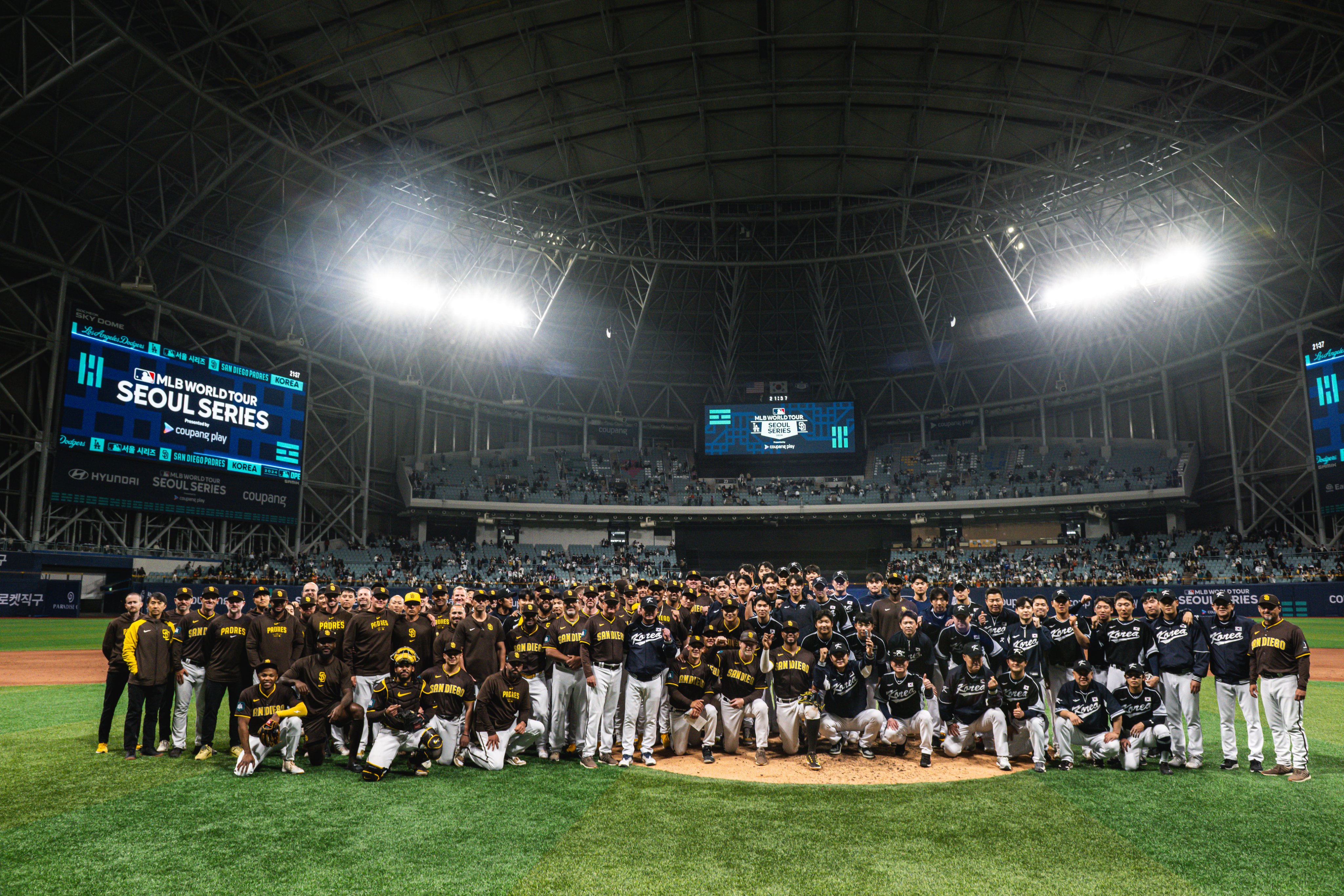 The Padres and Team Korea come together for a group photo on the mound at the Gocheok Sky Dome. On the video boards at the stadium is the MLB World Tour Seoul Series signage. 