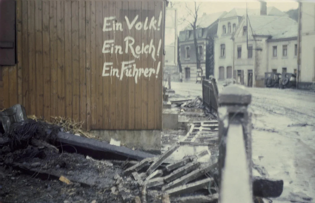 XharzH's tweet photo. Graffiti alemán pintado en la pared de un edificio de madera en una calle dañada por una bomba cerca del campo de concentración de Dachau.

El graffiti dice: "¡Un pueblo! ¡Un Imperio! ¡Un Lider!" https://t.co/BLwVT3VmJl