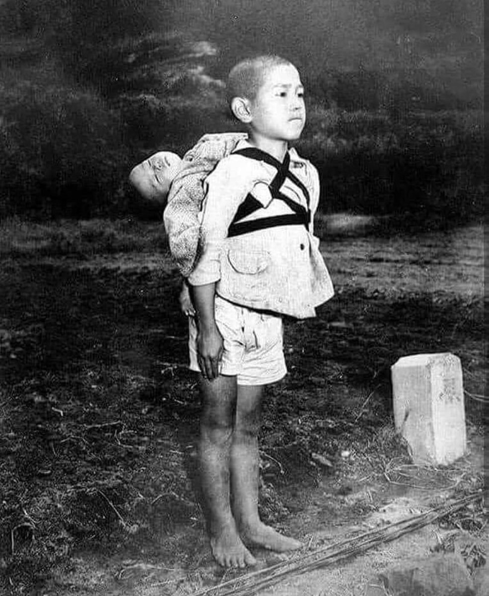 A barefoot boy waiting in line and staring ahead at a crematorium after the Nagasaki bombing, with his dead baby brother strapped to his back : This heartbreaking picture was taken by US Marine photographer Joe O’Donnell shortly after American forces dropped atomic bombs on…