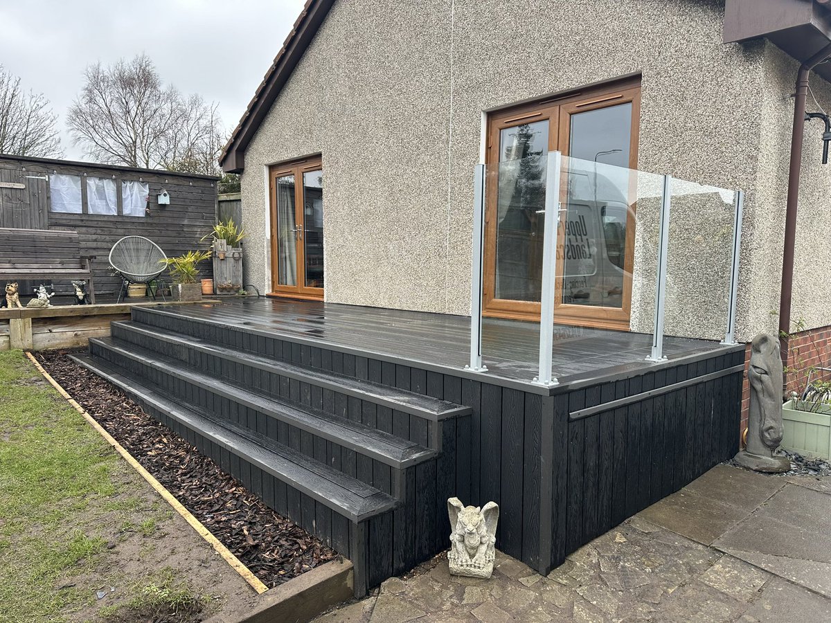 DeckLandscaping's tweet photo. Finishing off this black deck today. Our customer had 2 French doors fitted earlier in the year and looked to us to give them a great usable area that also leads into their garden. We also added this small section of glass balustrade from @SpectraglassLtd to really finish it off. https://t.co/49kQHbhWad