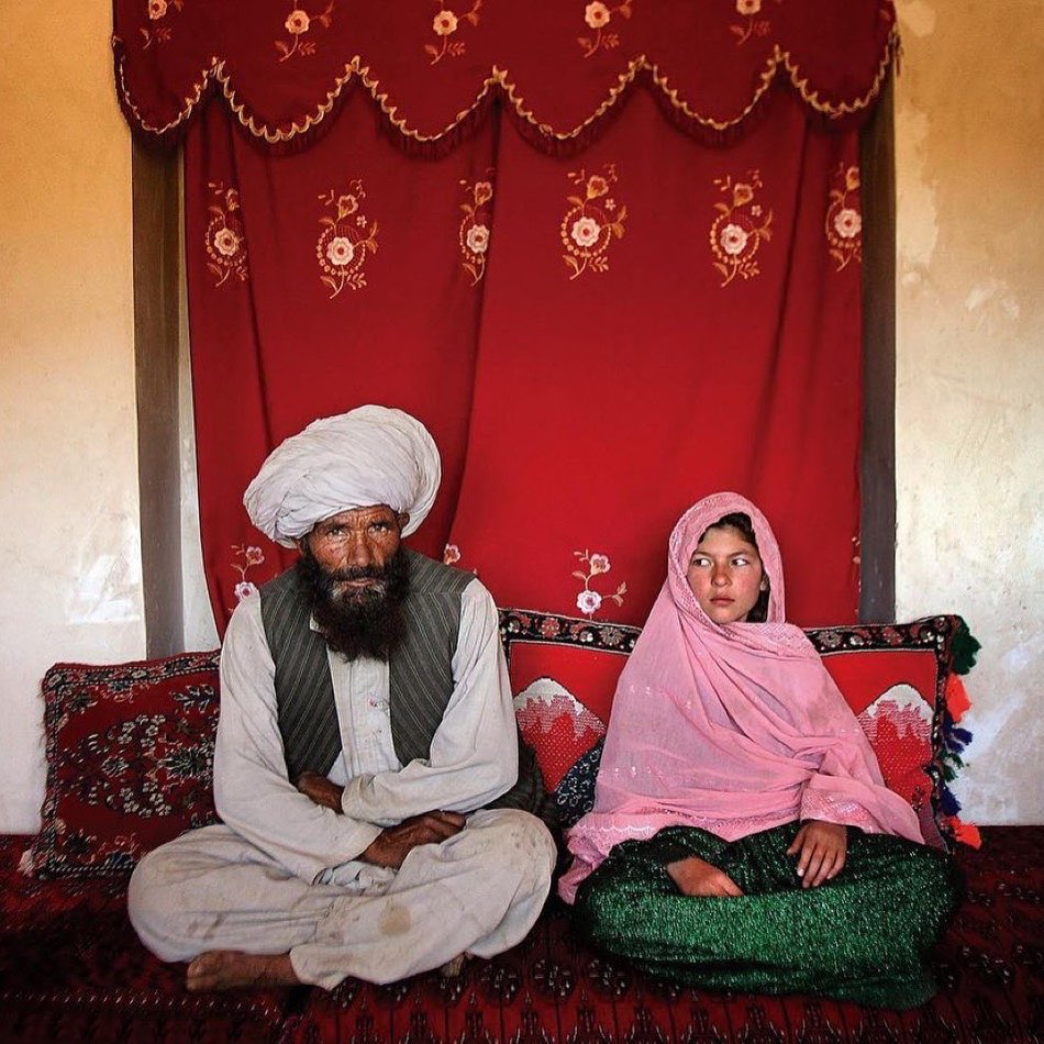 6. Una niña de 11 años de la provincia de Ghor, Afganistán, sentada junto a su prometido, de casi 50 años, en su ceremonia de compromiso poco antes de que la pareja se casara en 2005.