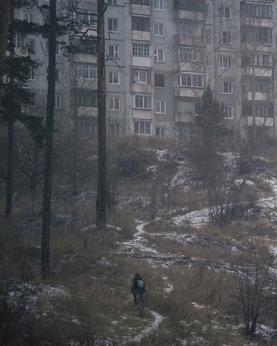 This is a photo that I particularly appreciate, for the dynamics of the figure ascending the snow-sprinkled hill, the verticality of the conifers perpendicular to the horizon of reiterative balconies like a giant wave of concrete