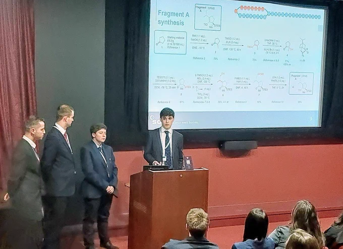 4 people standing in front of a total synthesis slide