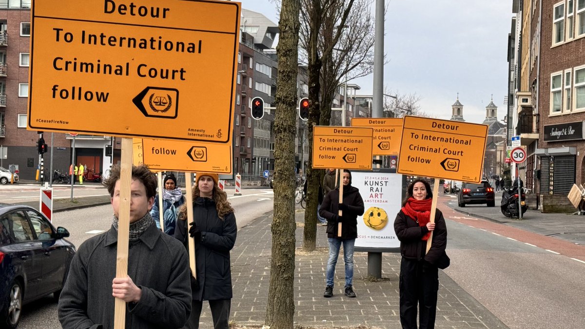 Mensen van ⁦<a href="/amnestynl/">Amnesty NL</a>⁩ staan langs de weg naar Nationaal Holocaust Museum in de hoop dat president Herzog van Israël langsrijdt. Ze vinden dat hij gezien zijn uitspraken over Gaza gearresteerd moet worden.