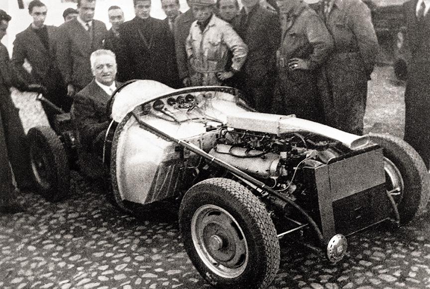 En 1947 se completaba la primera unidad del Ferrari 125S, primer coche con el nombre de Enzo en la historia, a quien vemos al volante en esta foto conmemorativa del momento.