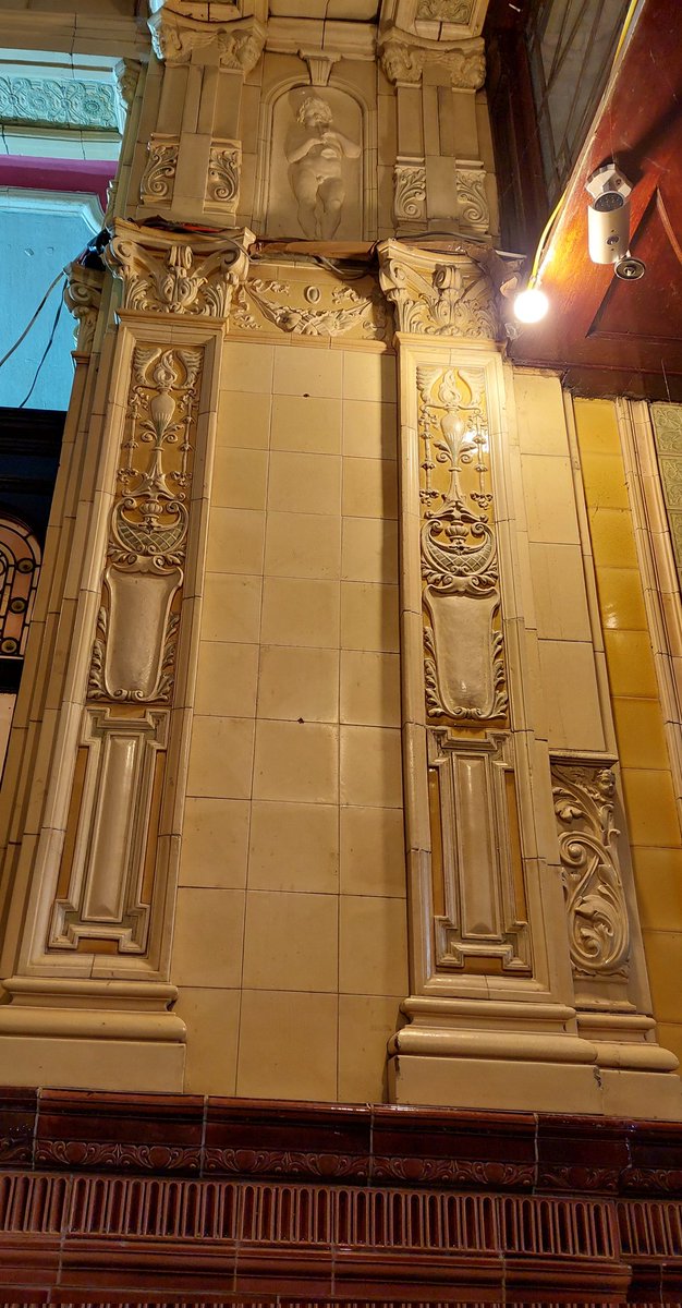 #TilesonTuesday #MorecambeWinterGardens An impressive central large embossed tile at the base of a pilaster. Way up top is the boy piper. A symphony in Ceramics. Let the music play.