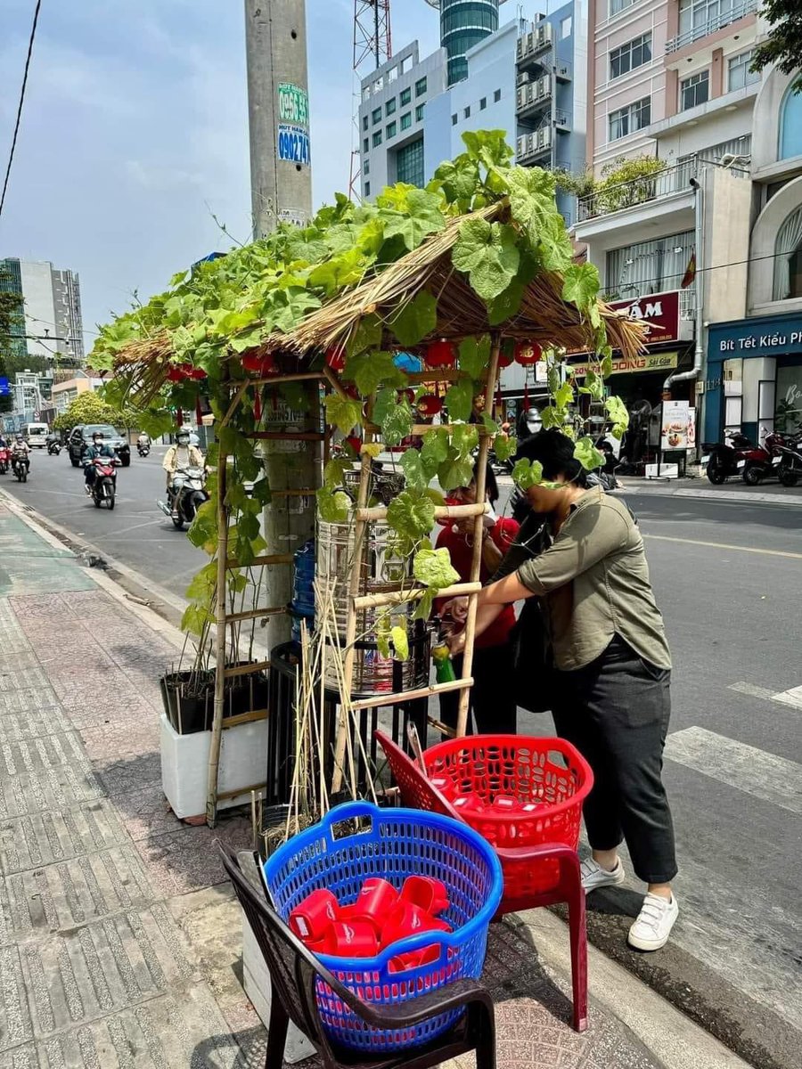 CelricTran's tweet photo. SÀI GÒN TỬ TẾ 
Một giờ trưa trời nắng nóng như đổ lửa, một bạn shipper tấp xe vào quán nước “Không Đồng” trước nhà thờ Mạc Ty Nho, bạn lấy ra chai nhựa rồi tự mở vòi hứng nước từ bình, bạn uống một hơi rồi lại hứng nước tiếp cho đầy và lên xe đi tiếp.

Hai bình nước một mát một lạnh trước nhà thờ Mạc Ty Nho rất độc đáo nó đặt dưới một mái lá nhỏ có hai chậu trồng nhiều dây bí thả bò phủ lên mái trông thật mát mắt làm dịu hẳn cái nóng chói chang.

Hai rổ lớn một đựng ly sạch một để ly xài rồi. Trong ly nước miễn phí còn có cả tấm lòng và sự tử tế của người Sài Gòn❤️

#saigon
