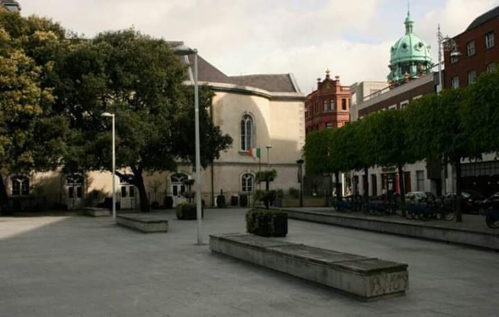 RobLooseCannon's tweet photo. Wolfe Tone Park, facing the Jervis Centre, holds macabre and fascinating secrets. It's home to "The Church" pub and the bulging bronze cow statue "Ag Crú na Gréine". Also, amid the occasional conclave of addicts the paved public space has some buried treasures. Lined up on the southern side and embedded in the pavement are dozens of gravestones. The park was originally a cemetery!  

The land was deconsecrated in 1966, but the thousands of bodies beneath were not exhumed. Some famous "residents" buried here are patriot and rebel Archibald Hamilton Rowan of the United Irishmen, Mary Mercer who founded Mercer’s Hospital and the notorious Lord Norbury (1745–1831) aka "The Hanging Judge". 

Nearby Jervis Street shopping centre is on the site of the former Jervis Street hospital. The Charitable Infirmary in Cook Street was founded by six Dublin surgeons in 1718 and moved to the former mansion of the Earl of Charlemont at 14 Jervis Street 1796. Jervis Street Hospital was eventually absorbed by Beaumont Hospital. Only the external facades were preserved when it became a shopping centre. For believers in the supernatural, there are numerous tales of alleged paranormal activity in the modern-day shopping centre related to its past incarnation.

The aforementioned park's illustrious namesake, Theobald Wolfe Tone (1763–1798) was baptised in the adjoining St. Marys church, as was playwright Sean O’Casey. Arthur Guinness (1725-1803) married Olivia Whitmore there in 1761. 

Saint Mary’s Church of Ireland was built around 1704 but closed in 1986 due to a lack of C.of I. parishioners in the city centre. It was bought by publican John Keating in 1997 and received a generous and faithful restoration whilst being converted to a pub and restaurant. 

Back to the subject of graves, Wolfe Tone Park isn't the only resting place. Although the subterranean Cellar Bar in the Church is not actually the old crypt, there were six genuine, well stocked burial crypts in its basement. 32 skeletons were exhumed and reinterred elsewhere during deconsecration.