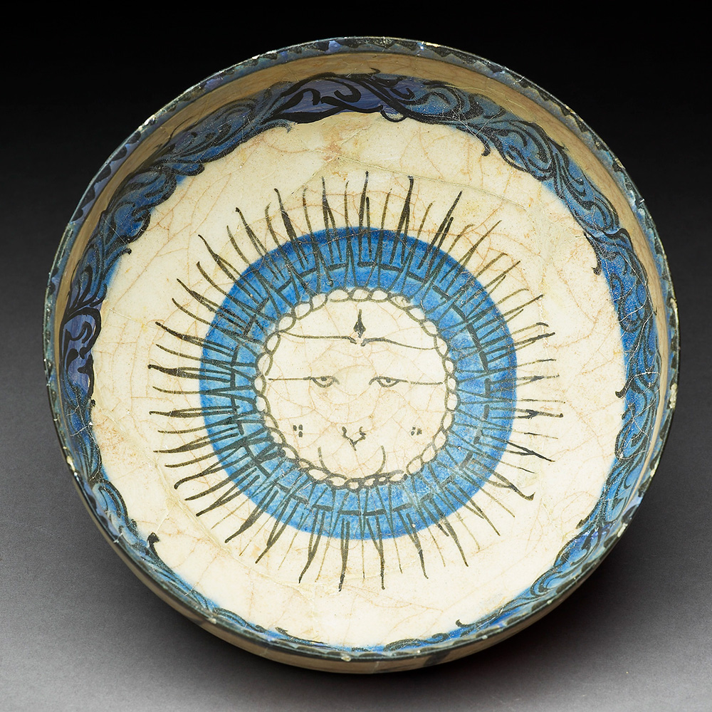 A smiling sun sits at the centre of this 13th century bowl.

Here, the sun acts as a symbol of good fortune for the owner of the bowl, acting as a reminder of the heavens.

This type of decoration - blue and black painting under glaze was a technique developed in Iran around