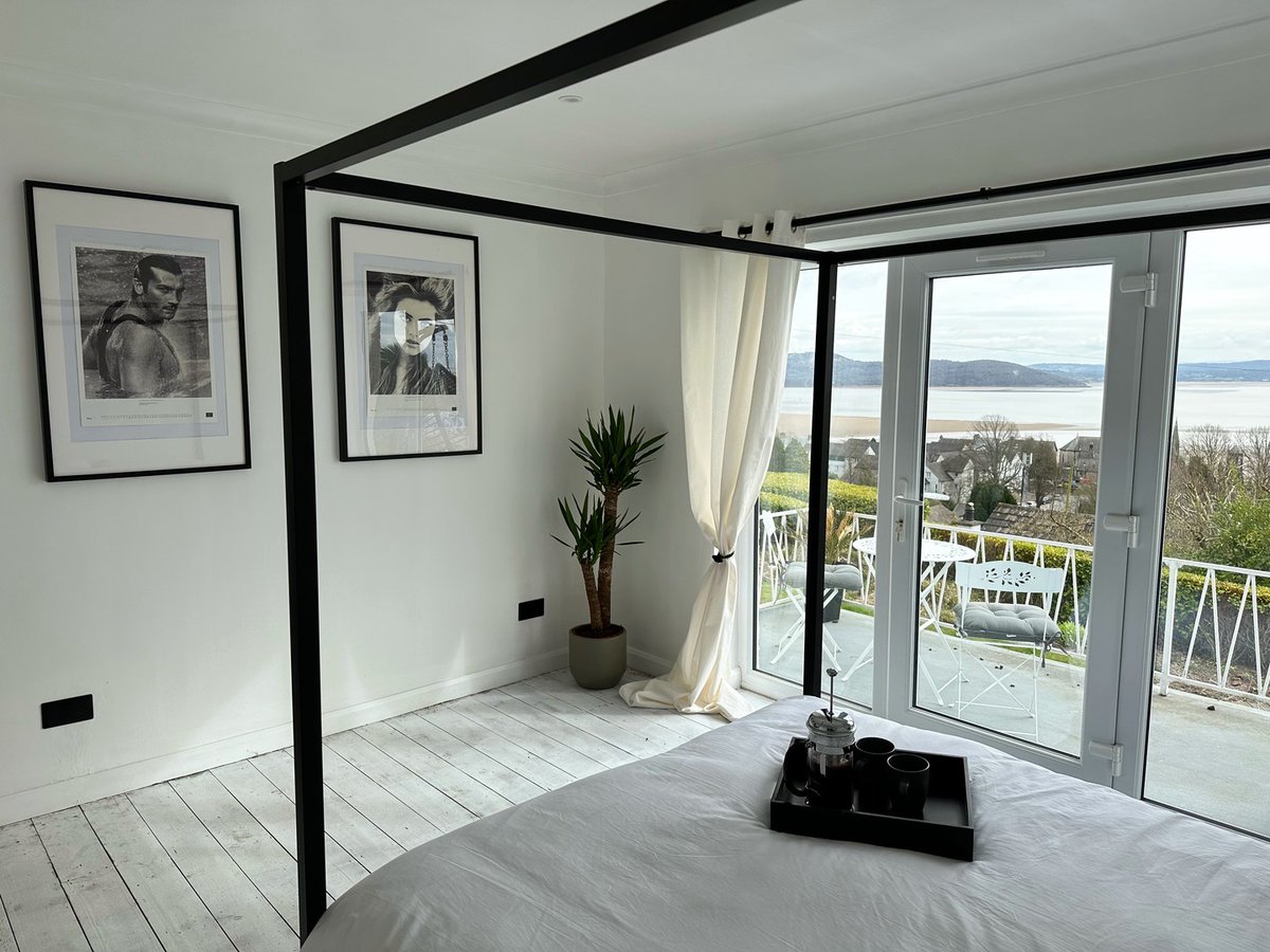 Here's the view from the master bedroom at Cragg View. A four poster bed and walls adorned with award-winning artwork 🇬🇧 Not to mention fabulous views right across Morecambe Bay from your own balcony! #lakedistrict #grangeoversands #morecambebay #accommodation #airbnb #vrbo