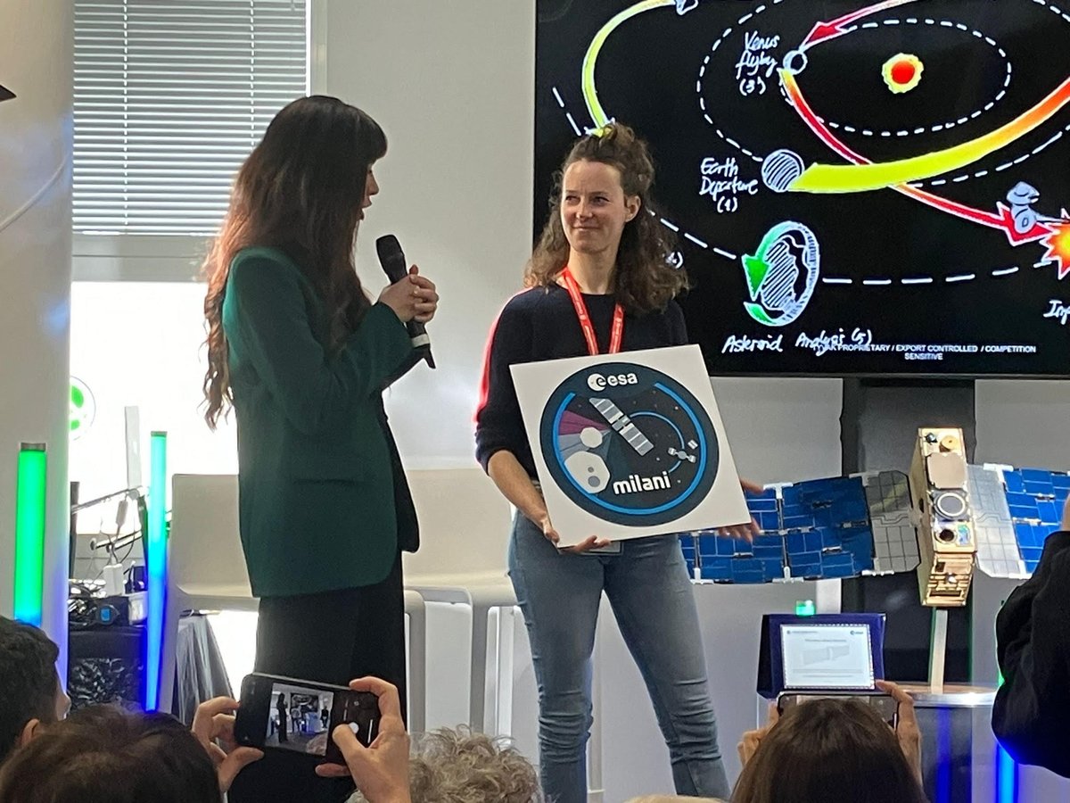 ESA_nl's tweet photo. Alice Milani, dochter van de man naar wie de #Milani CubeSat van #HeraMission is vernoemd, toont het winnende ontwerp van de #MilaniPatchContest. Wijlen Prof. Andrea Milani bedacht #DARTmission &amp; Hera voor #PlanetaryDefence https://t.co/ERA6nLXfrj https://t.co/rJzbe254UO