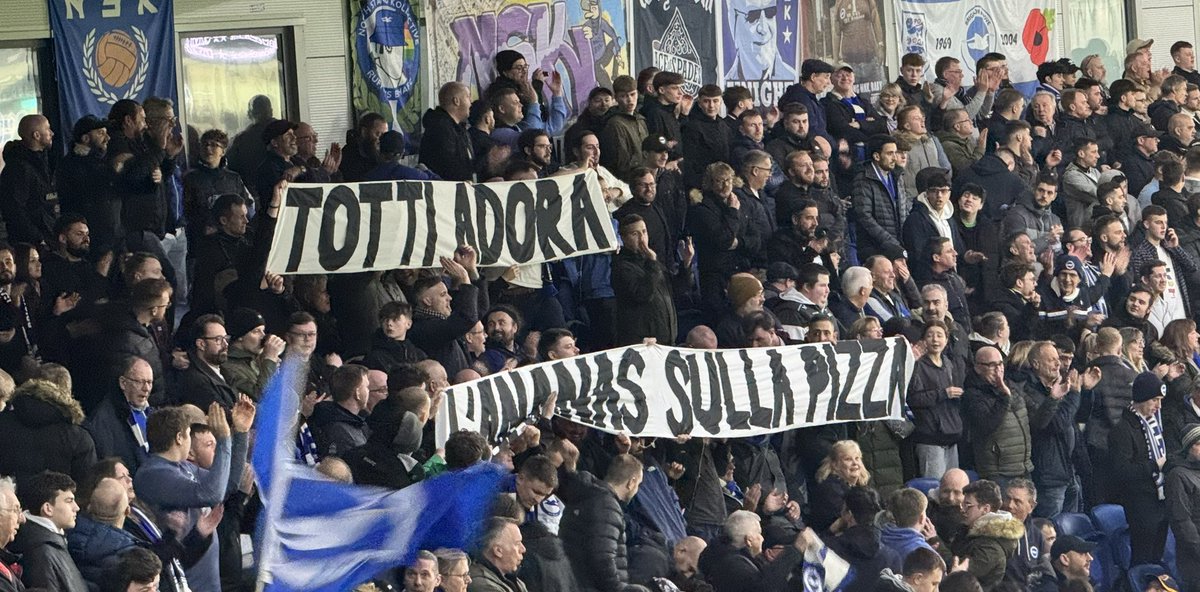 Brighton fans respond to the rude banner about the Queen displayed by Roma fans last week with terrace humour reply of ultimate insult to an Italian “Totti loves pineapple on pizza”