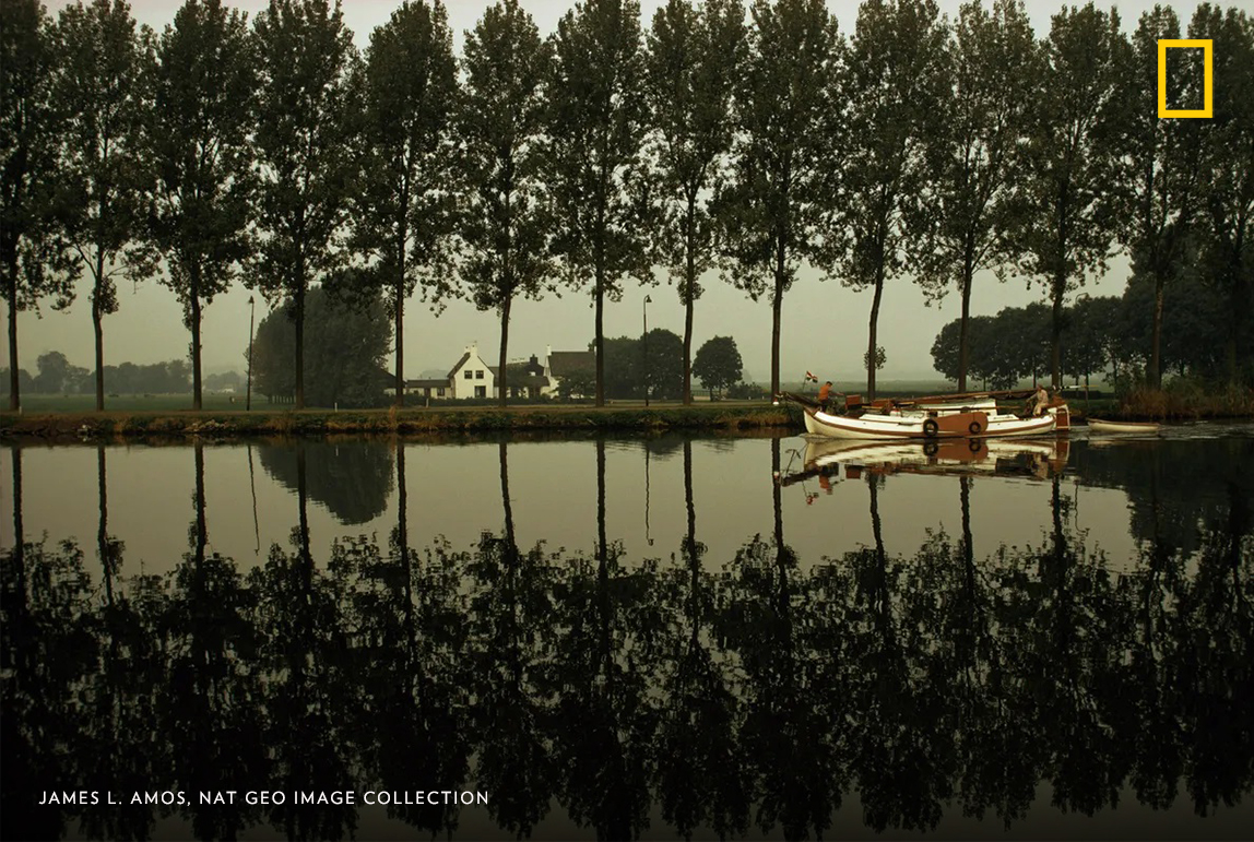 #PhotoduJour | Conçu pour naviguer sur les eaux peu profondes, ce tjalk passe devant les peupliers qui bordent le fleuve Amstel, à Amsterdam, aux Pays-Bas. Ce cliché a été pris pour un article paru en mai 1974 sur la vie dans la ville néerlandaise.