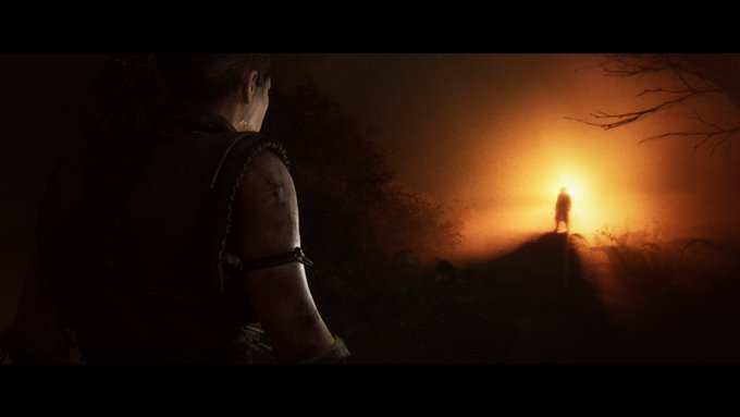 Senua approaches the silhouette of a figure stood in a wooded area, backlit by a bright orange light.