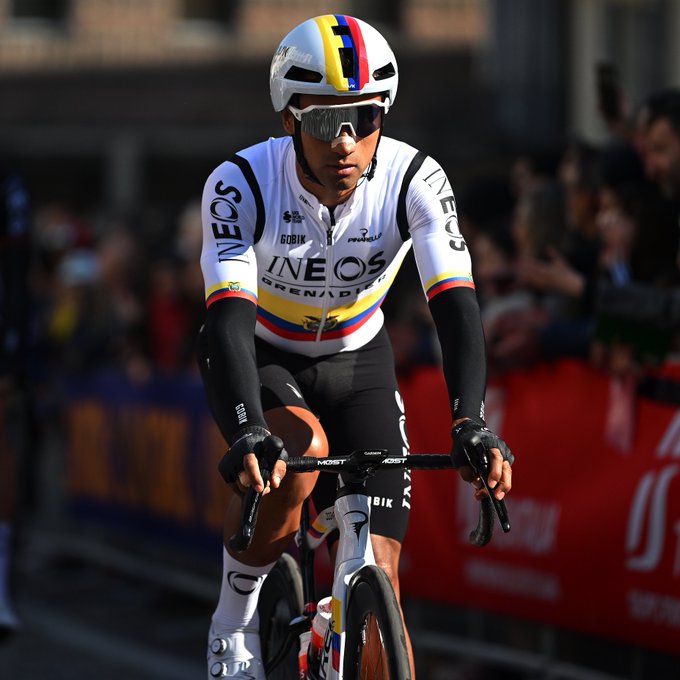 Jhonatan Narvaez riding to the start of Milan-San Remo wearing his Ecuadorian national champion kit, which is white, with the Ecuador flag represented with a red, blue and yellow horizontal flag line across the centre of the jersey. His helmet is white with a matching vertical flag which is displayed as a central stripe down the top of the helmet. 