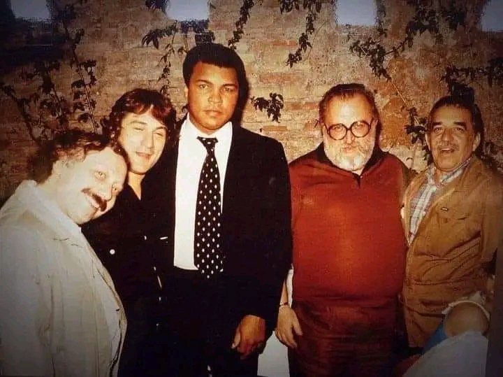 El periodista y escritor Gianni Mina cuenta la historia detrás de esta foto: 《Robert De Niro estaba en Roma para filmar 'Érase una vez en América', de Sergio Leone. Una noche me llamó: —Gianni, ¿cómo estás? ¿Qué estás haciendo hoy? —Vamos a cenar, respondí, estoy con Muhammad…