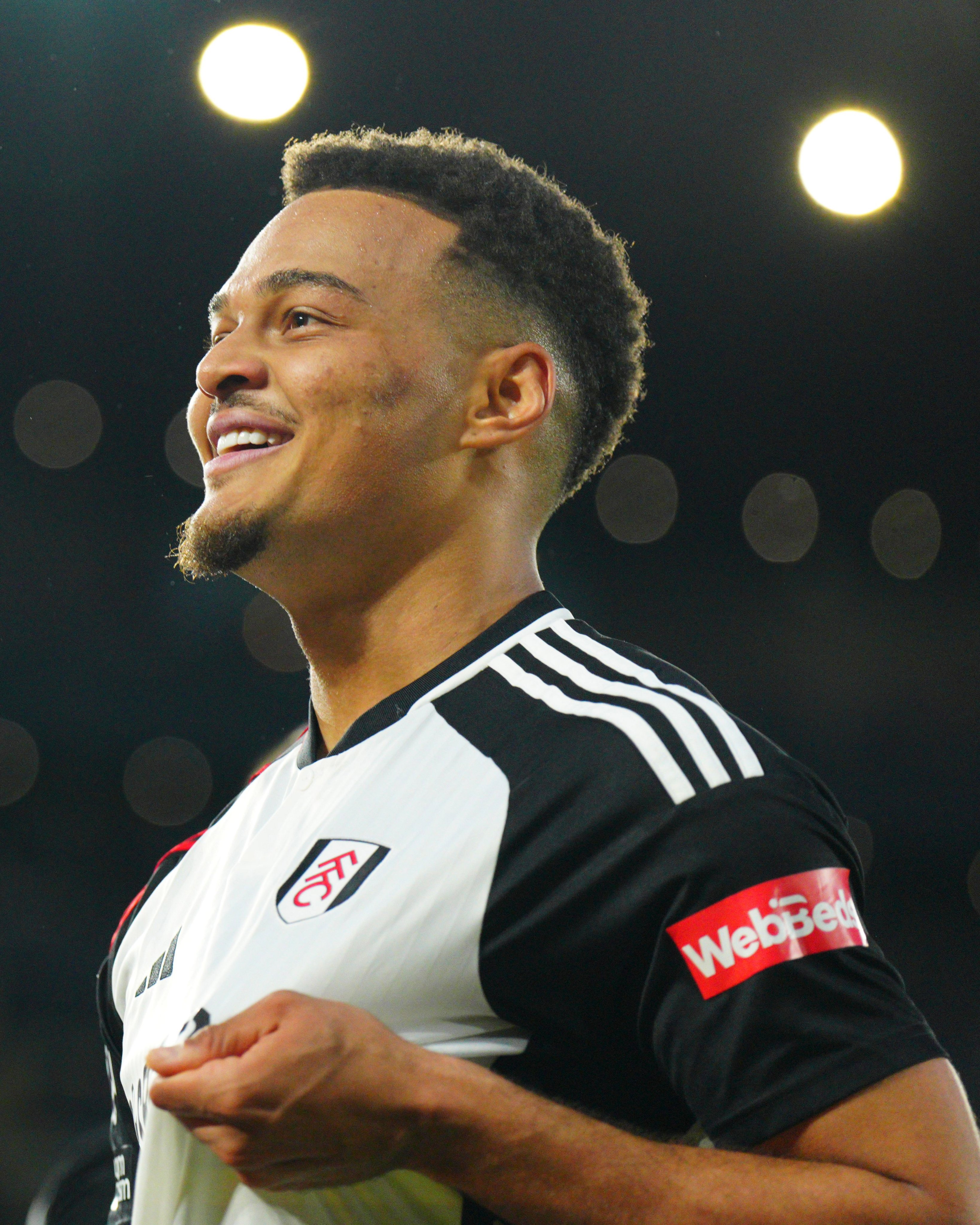 A beaming Rodrigo Muniz grabs the Fulham badge after scoring against Tottenham.