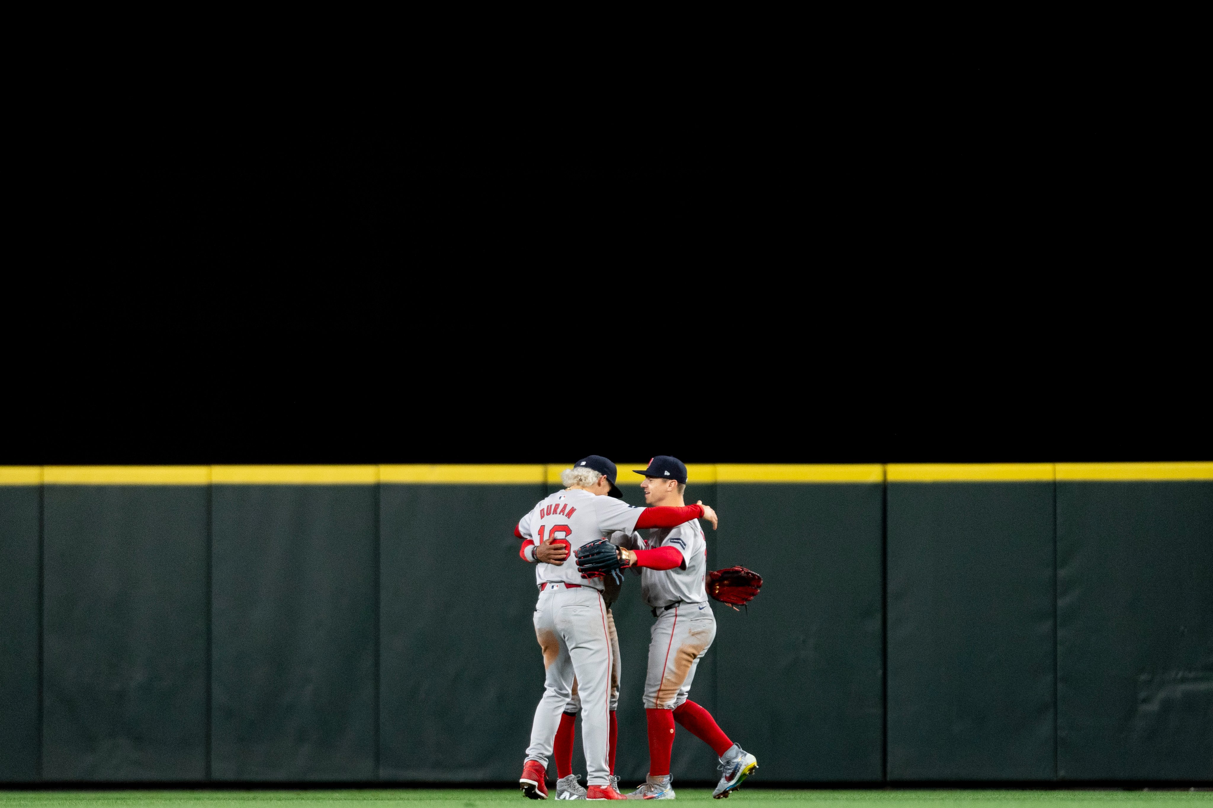 From left to right: Jarren Duran, Ceddanne Rafaela, and Tyler O'Neill hug in the outfield after the Red Sox Opening Day win against the Mariners. 