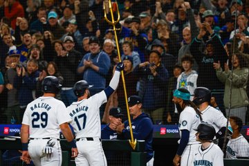 Photo of Mitch Haniger raising the trident towards the fans. 