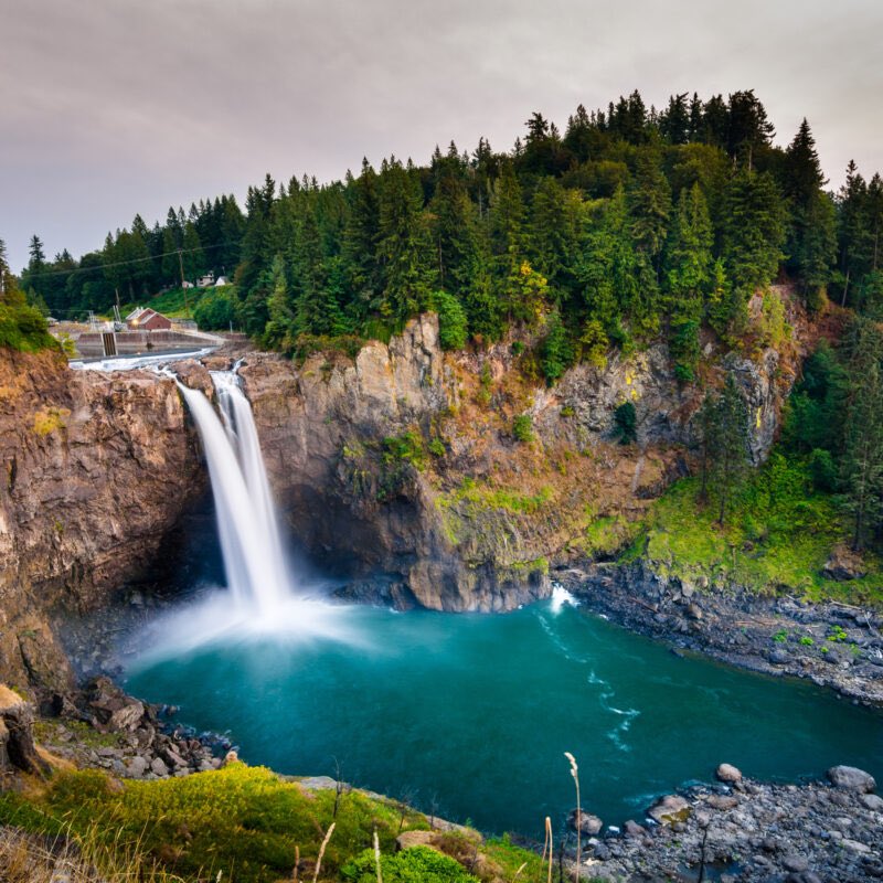 Standing at the precipice, enveloped in mist, watching the mighty Snoqualmie Falls cascade down, a symphony of nature's raw power and beauty. The roar of rushing water echoing against the cliffs, a testament to time's enduring force. Each droplet, a transient dance between sky…