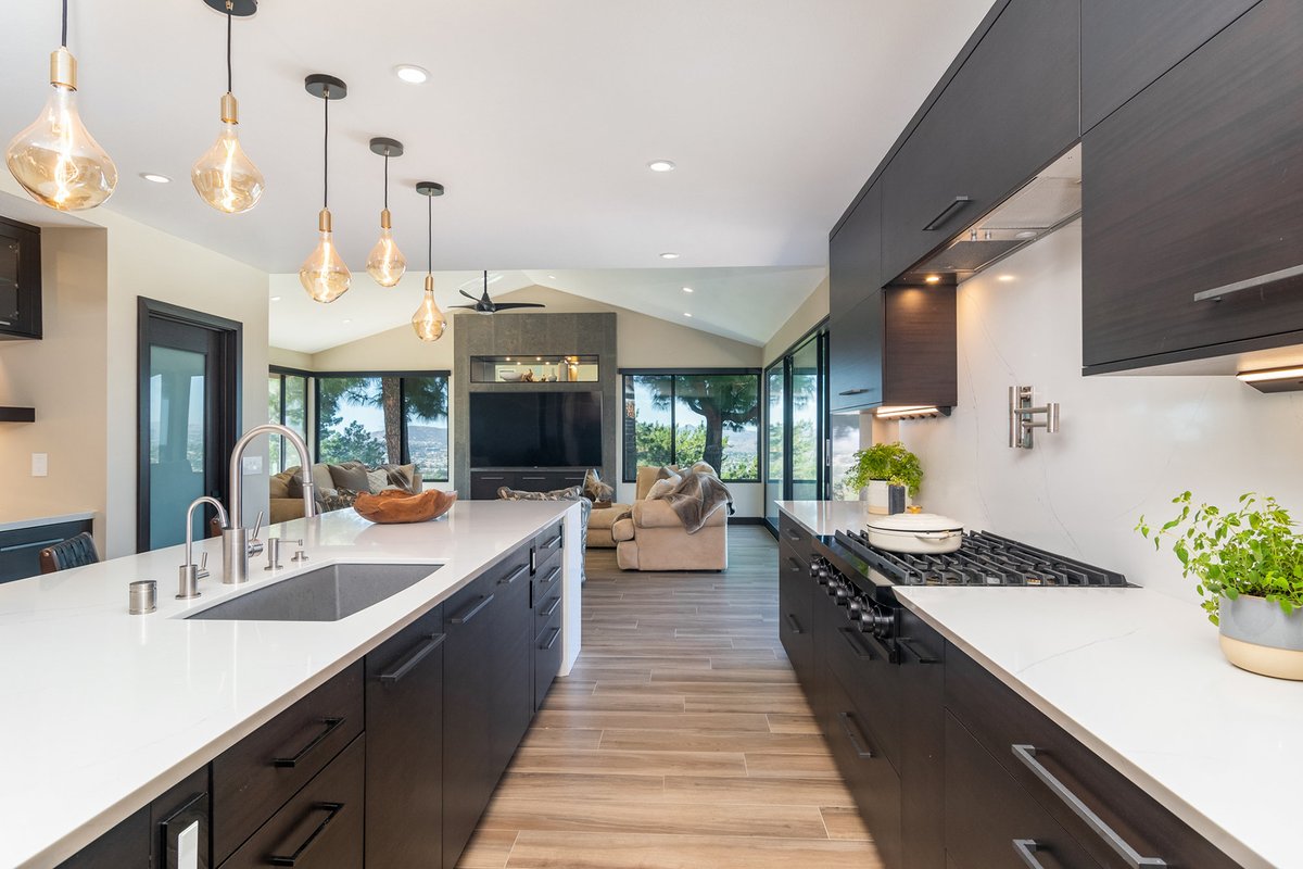 This sleek contemporary kitchen is open to a living space with a beautiful view.